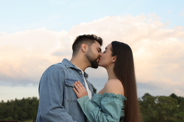 Romantic date. Beautiful couple kissing against blue sky with clouds