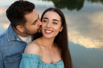 Romantic date. Beautiful couple spending time together near lake