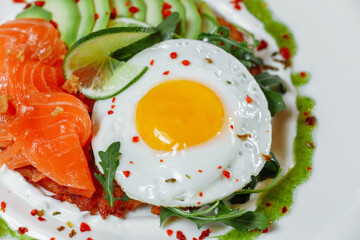 Poached eggs on top of smashed avocado on sourdough toast with smoked salmon. Healthy breakfast with plate on table. Top view. Copy space to right 