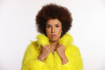 Portrait of beautiful young woman in stylish yellow fur coat on white background