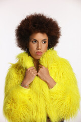 Portrait of beautiful young woman in stylish yellow fur coat on white background