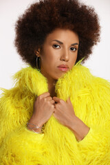 Portrait of beautiful young woman in stylish yellow fur coat on white background
