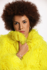 Portrait of beautiful young woman in stylish yellow fur coat on white background