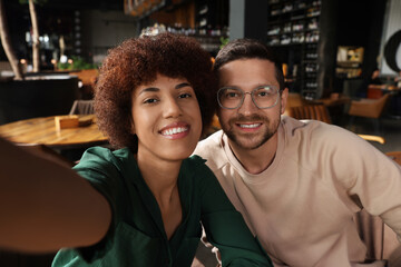 Fototapeta premium International dating. Happy couple taking selfie in cafe