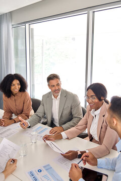 Busy international professional executive team diverse colleagues employees work group consulting planning strategy, having discussion at office corporate board room meeting. Vertical shot.