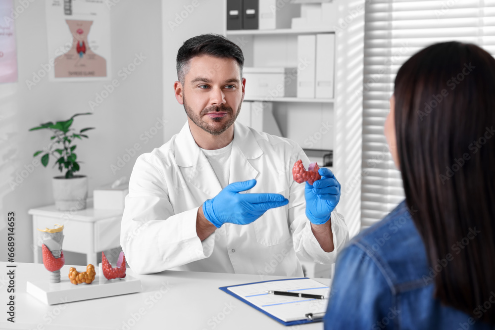 Wall mural Endocrinologist showing thyroid gland model to patient at table in hospital