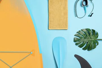 Flat lay composition with SUP board on light blue background. Water sport