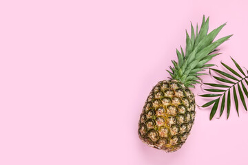 Whole ripe pineapple and green leaves on pale pink background, flat lay. Space for text