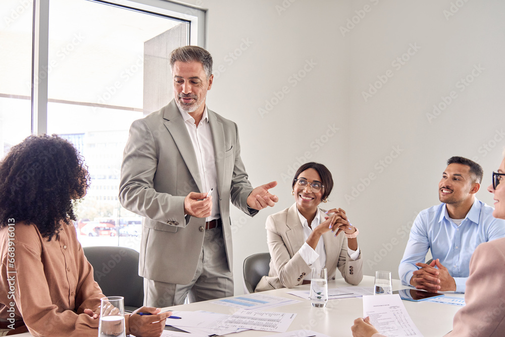 Wall mural senior older indian business man director boss ceo leading employees team meeting presenting company