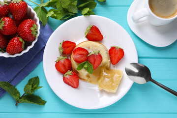 Tasty vanilla fondant with white chocolate, strawberries and cup of coffee on light blue wooden...