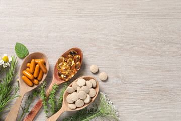 Different pills, herbs and flowers on wooden table, flat lay with space for text. Dietary supplements
