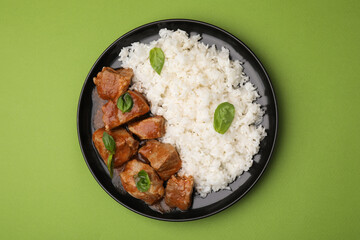 Delicious goulash with rice on green background, top view