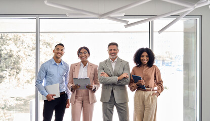 Four international successful company workers and leaders business people executive team colleagues standing in office. Happy confident diverse professional employees group corporate portrait.