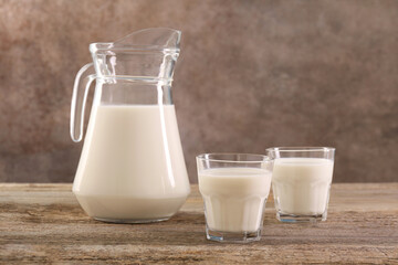 Obraz na płótnie Canvas Jug and glasses of fresh milk on wooden table