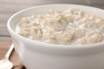Tasty boiled oatmeal in bowl on table, closeup