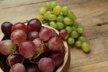 Different fresh ripe grapes on wooden table, closeup. Space for text