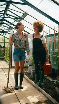 Vertical Video Portrait Of Two Female Friends Or Same Sex Couple Working Gardening In Greenhouse At Home Together - Shot In Slow Motion