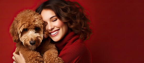 Smiling woman lovingly embraces her brown Spanish water dog against a red background representing love for animals