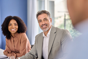 Busy happy diverse international executive team people communicating in office having discussion in boardroom. Business conversation of professional employees group talking working at group conference