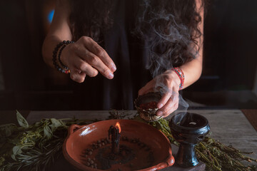 woman doing traditional ritual with black candle sea salt pepper in clay plate with herbs and...