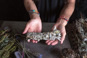 woman doing traditional ritual with herbs tying them with cotton thread accompanied by incense