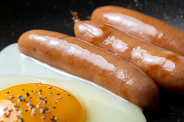 フライパンでウインナーと目玉焼きを焼く調理シーンのアップ。
