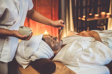 Crédence de cuisine en verre imprimé Spa Serene ambiance of spa salon, woman customer indulges in rejuvenating with charcoal face cream massage with warm lighting candle. Facial skin treatment and beauty care concept. Quiescent