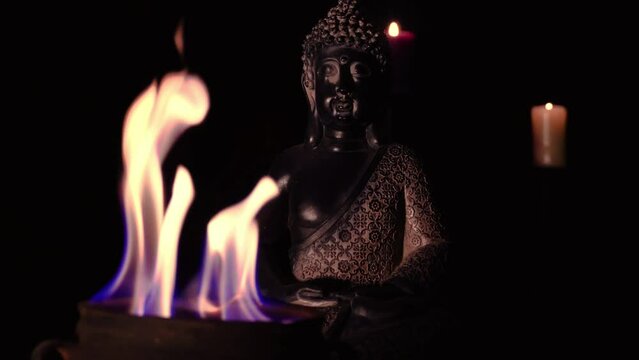 buddah figure meditating in dark temple with fire and candle