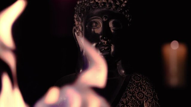 buddah figure meditating in dark temple with fire and candle