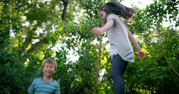 Trampoline, happy or children play in backyard for fun games on holiday to relax together. Wellness, bounce or excited kids in nature or kindergarten for jumping game, playing or activity for freedom