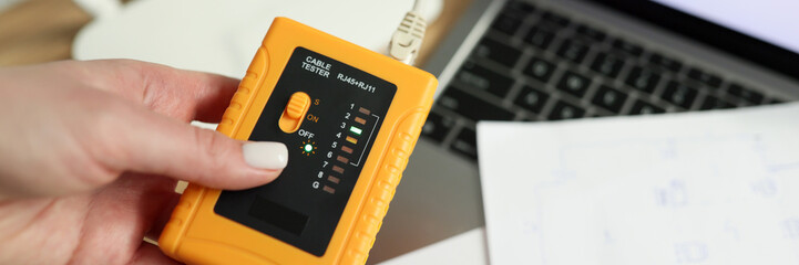 Woman holds LAN speed tester near Wi-Fi router and laptop