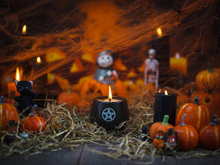 Halloween. Happy Halloween decoration at party with lot of pumpkins and black candles, soft focus on the candle with pentacle sign in center, blurred background is grim the reaper. Copy space.
