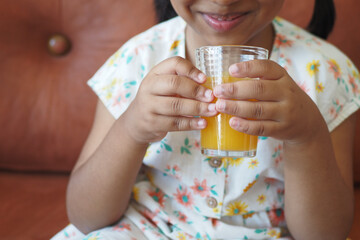 child hand holding a glass of orange juice 
