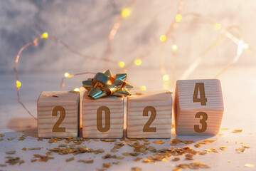 New Year holiday background. Inscription on wooden cubes of the number 2023 and 2024 with bright...