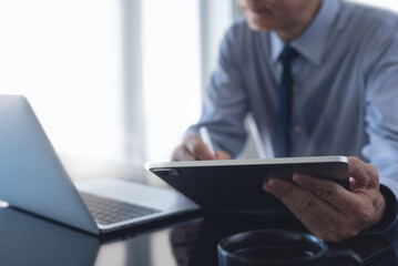 Businessman using digital tablet and working on laptop computer at modern office. Business man, project manager planning new work project on tablet pc at workplace