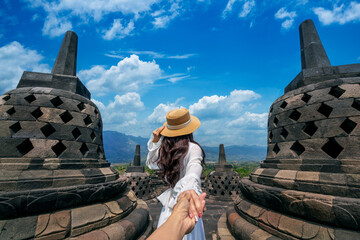 Women tourists holding man's hand and leading him to Borobudur Temple in Java Indonesia.
