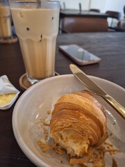 Breakfast with croissant and coffee. half-eaten criossant.