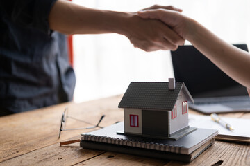 A bank loan officer shakes hands with a customer to congratulate him after approving a home loan. A...