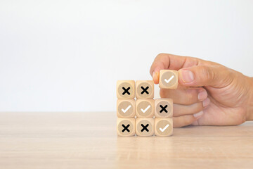 Hand choose check mark with cross symbol on cube wooden block stack for true or false changing...