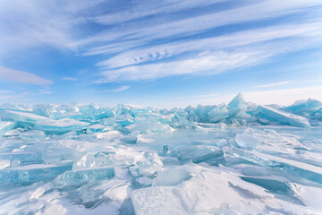 Winter cold seascape with pile of blue ice floes on frozen Baikal Lake against backdrop of blue sky...