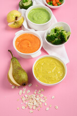 Bowls with baby food on pink background. Healthy eating concept.
