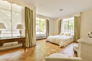 a bedroom with two beds and a table in front of the window that overlooks out onto the hardwood floor