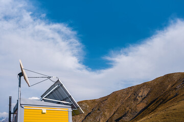An antenna and solar batteries on the roof of a lodge in the mountains