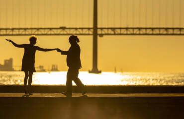 Fototapeta premium Silhouettes of dancing elderly couple holding hands on sunset