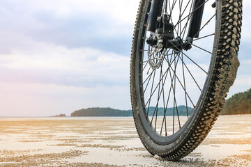 Front wheel of a mountain bike on a sandy beach in Thailand. The concept of cycling in unusual...