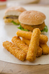Portobello hamburger with cheese and cheese sticks on a table