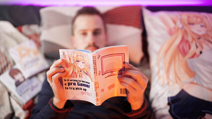 Reading Japanese manga comic while in bed with anime waifu hug pillow