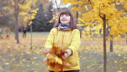 Joyful Woman Throwing Autumn Leaves Playfully in the Park