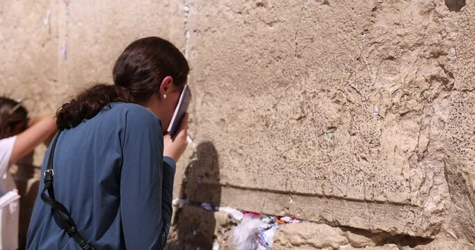 Orthodox Jew facing the Western wall praying. Jewish Girl praying. Other religious women in background pray to the Kotel. Wailing wall Jerusalem, Jerusalem, Israel. God's religion and conflict