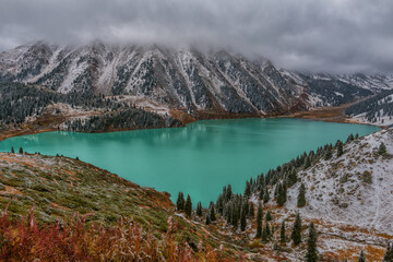 Picturesque mountain lake on a cloudy autumn day during the first snowfall